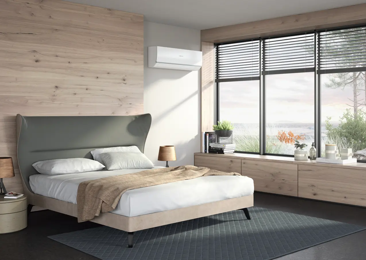 Viessmann Klimagerät an der Wand über einem Doppelbett in modernem Schlafzimmer, mit Fensterfront und natürlichem Licht, durch Jalousien gefiltert.
